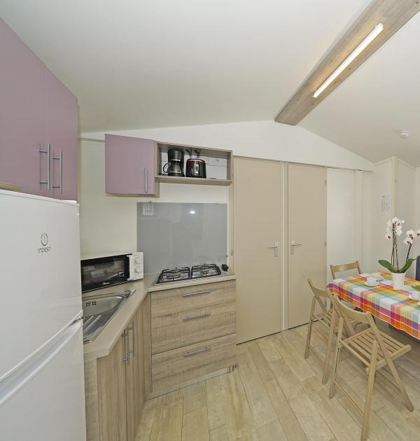 Compact kitchen with colorful table, sofa, and appliances.