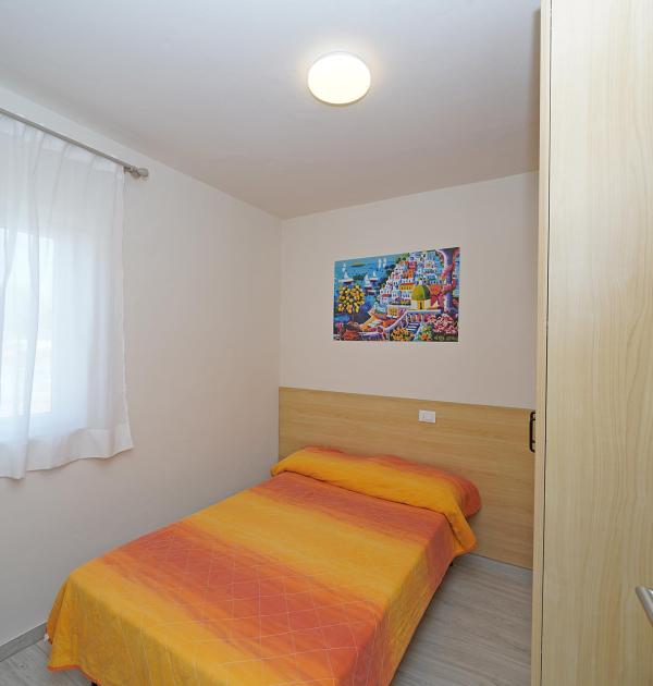 Einzelzimmer mit orangefarbenem Bett und buntem Gemälde.